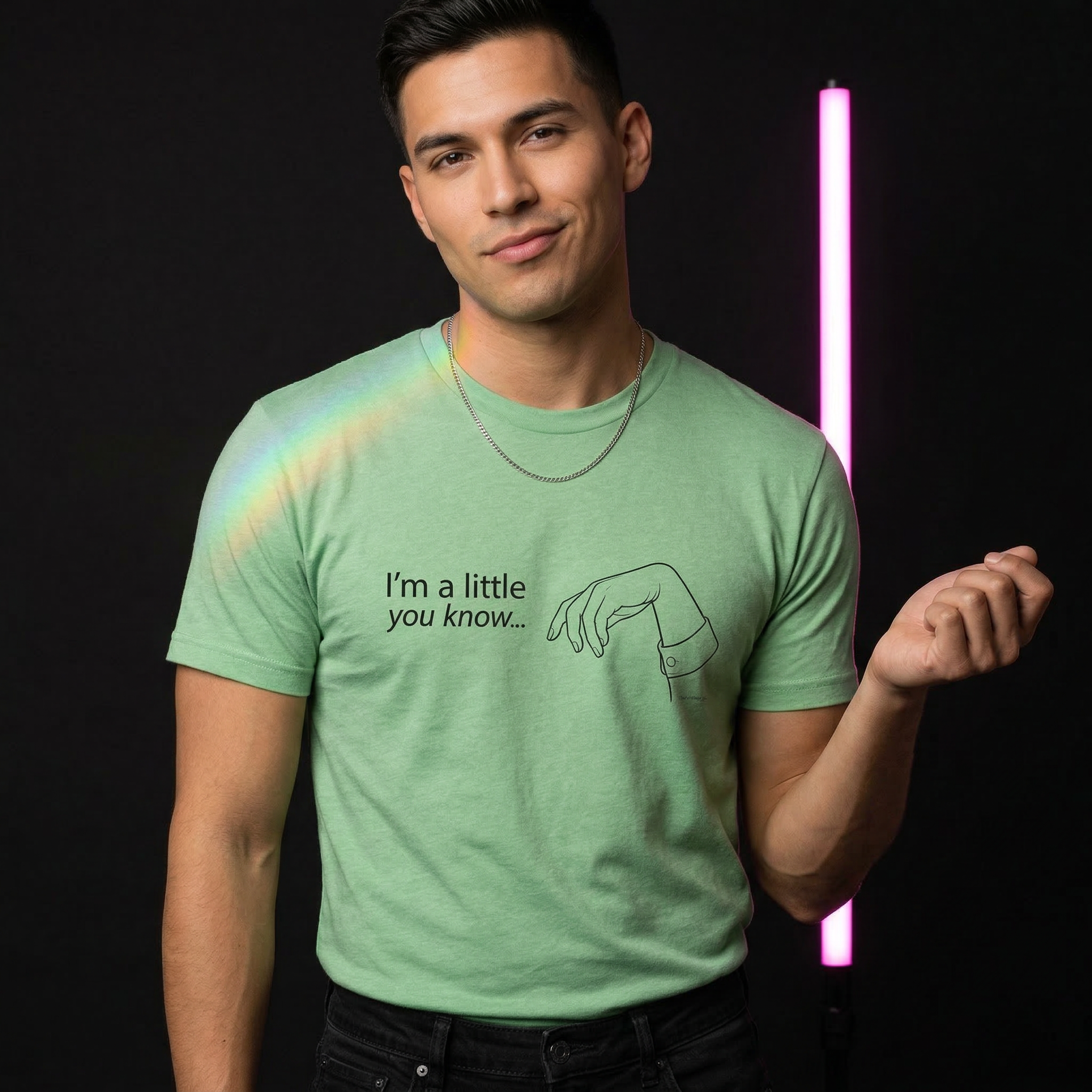 Man wearing a green t-shirt with text and graphic, standing against a dark background with neon light. X Collection: Limp Wrist Tri-Blend Graphic Tee. Funny gay shirts, funny pride shirts, pride t-shirts by Pride Clothing Co. 